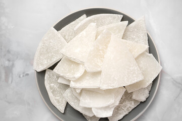 Top view of a plate on a light background with pieces of peeled coconut