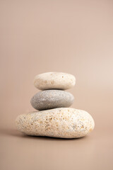 Fototapeta na wymiar Pyramid of sea pebbles. Isolated on a beige background. The concept of life balance and harmony