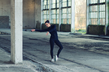 Ballerina stretching and dancing in an abandoned building on a sunny day