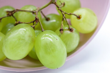 closeup bunch of green grapes in a pink bowl (diet or healthy food concept)