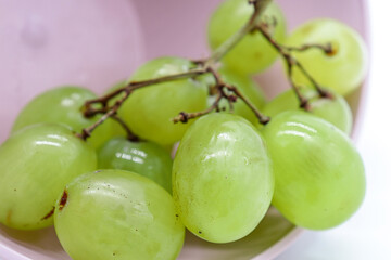 closeup bunch of green grapes in a pink bowl (diet or healthy food concept)