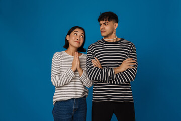 Young multiracial couple frowning and making pray gesture