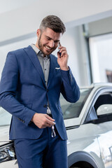 Businessman and his new car that he just bought in showroom.