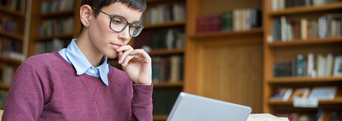 Young woman student reads books and study in the library