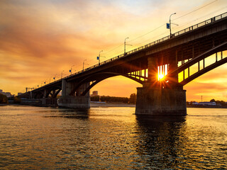 Arched October road bridge over the Ob River in the big city Novosibirsk at sunset,
