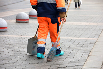Janitor woman with broom and scoop on a autumn street. Cleaning the city, street sweeper on people background