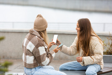 Teenager girls friends spending free time together outdoor, using smart phones looking at the...