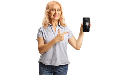 Casual mature woman holding a smartphone and pointing at the broken screen