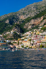Fototapeta na wymiar Positano on the famous Amalfi Coast in Campania Italy. Picturesque historic village in world heritage area with colorful houses built on the coastline. Harbour and beech seen from a tourist ferry.