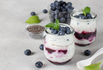 Chia pudding with blueberry and jam in two glass jars gray background, Concept of healthy vegan breakfast