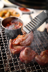 Korean table setting with grilled pork golden brown on the grill and side dishes set 그릴 위 노릇노릇하게 돼지고기를 굽고 있고 반찬이 세팅되어 있는 한상차림