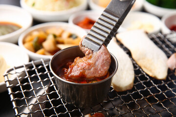Korean table setting with grilled pork golden brown on the grill and side dishes set 그릴 위 노릇노릇하게 돼지고기를 굽고 있고 반찬이 세팅되어 있는 한상차림