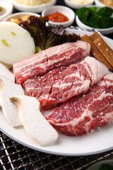 Korean table setting with grilled pork golden brown on the grill and side dishes set 그릴 위 노릇노릇하게 돼지고기를 굽고 있고 반찬이 세팅되어 있는 한상차림