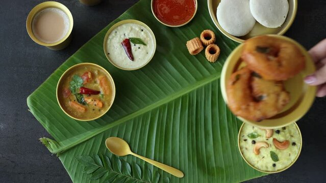Medu Vada with tiffin sambar coconut chutney in banana leaf background , 4k video of savory fried tea time snack of Kerala, Tamil Nadu South India. Top view of Indian veg breakfast food.