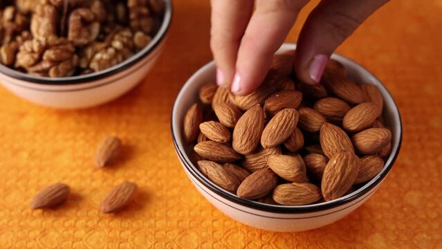 4k video of women taking almond or badam nuts from white bowl. Indian nuts.