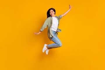 Full body portrait of cheerful gorgeous lady have fun good mood jumping isolated on yellow color background