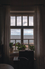 window with glass and a wooden table, flowers on the windowsill and a sewing machine on the table