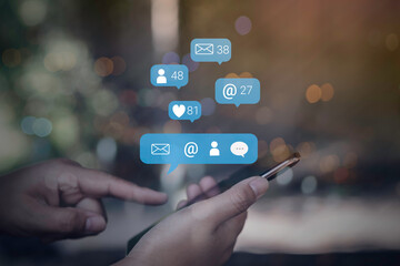 Person using a social media marketing concept on mobile phone with notification icons of like, message, comment and star above smartphone screen.
