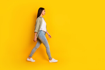 Full size profile photo of pretty charming person look walking empty space isolated on yellow color...