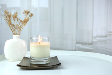 luxury lighting aromatic scented candle is on gold ceramic tray white metal table with ceramic vase...