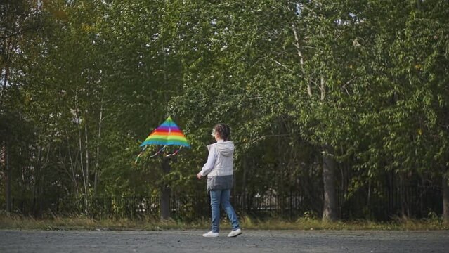 a child in a vest goes backwards launches a kite in the park