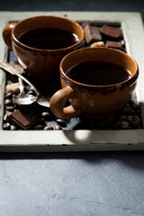 fresh black coffee in a cups and chocolate on blackboard, vertical