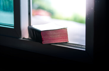Bible on the window sill with light in the morning time, the book of life, the voice of god, the teachings of god, spiritual food.