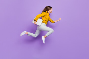 Full size profile portrait of crazy energetic girl hold netbook hurry rush jump empty space isolated on purple color background - obrazy, fototapety, plakaty