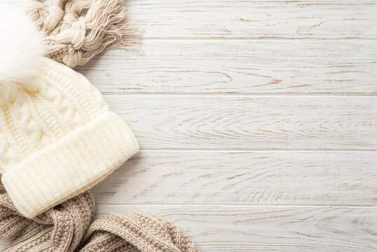 Winter concept. Top view photo of white bobble hat and knitted scarf on white wooden table background with copyspace - Powered by Adobe