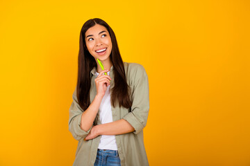 Photo of positive nice person pen touch chin toothy smile look empty space isolated on yellow color background