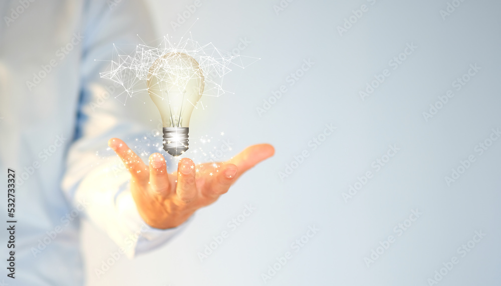 Wall mural Concept of idea innovation and inspiration Man's hand holding an illuminated light bulb, concept creativity with glittering bulbs. Inspiration for long-term business development.