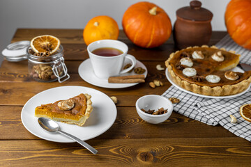 Pumpkin pie with whipped cream and cinnamon on a white plate, top view. Homemade fall baking for Thanksgiving - a piece of pumpkin pie.