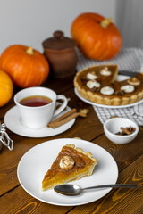 Pumpkin pie with a cup of tea on a wooden table