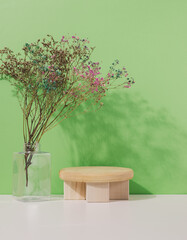 Stage for displaying products, cosmetics with a round wooden podium and a glass vase