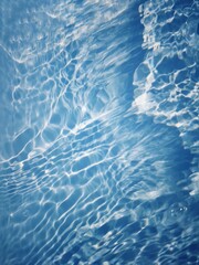 Bluewater waves on the surface ripples blurred. Defocus blurred transparent blue colored clear calm water surface texture with splash and bubbles. Water waves with shining pattern texture background.