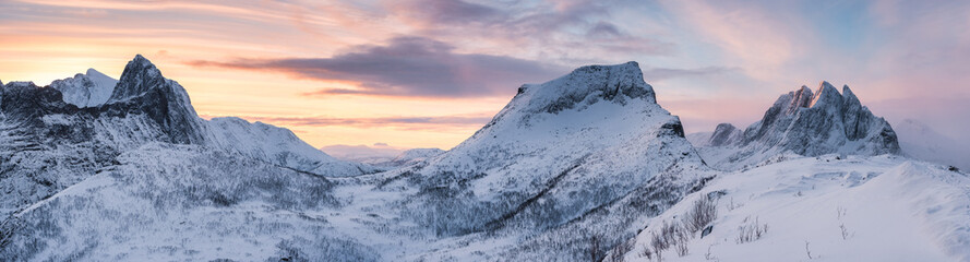 Panorama of sunrise over snowy mountain range with colorful sky in winter on Segla Mount at Senja Island