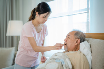 Female caregiver giving senior man medical pills,Medical assistance for elderly people,Routine health check and giving medication.