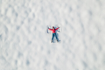 Woman lying on a snow and doing angel print on a snow covered land. Aerial, top view. Drone photo. Winter - 532738135