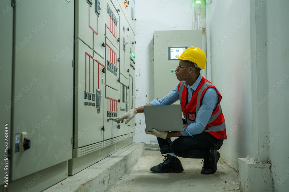 Poster engineer working in electrical room with power energy motor machinery cabinets with panel in control