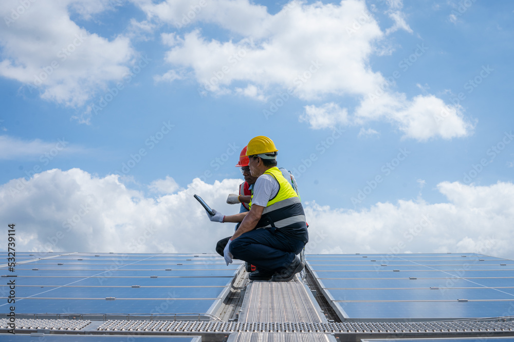 Poster engineer with technician working and maintenance with solar batteries near solar panels at sunny day