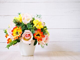 Pastel colored artificial flowers bouquet in pot on table, copy space for text or lettering pretty...