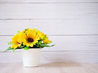 Yellow colored artificial Sunflowers bouquet in pot on table, Decoration copy space for text or lettering pretty background or wallpaper ,mother's day ,still life ,women's day festive background 