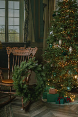 Beautiful home interior of living room with decorated Christmas tree and wreath on vintage chair. Festive holiday background.