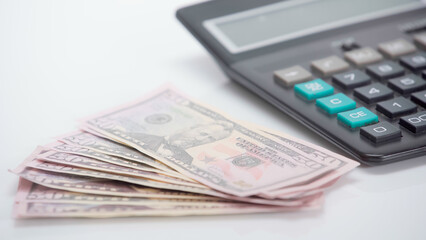 dollar banknotes near blurred calculator on white background.