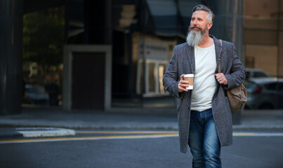 confident mature businessman man walking in city street holding coffee enjoying urban lifestyle