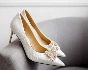 Beige shoes. Nude heels for a wedding with gold decoration stand on a gray chair