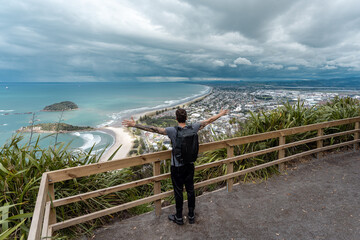 Fototapeta na wymiar Man with open arms at Mount Maunganui lookout on a beautiful day. New Zealand