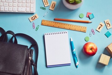 Computer keyboard, backpack, paper notebook, pen, pencil, wooden ruler and apple top view photo. School, college table flat lay image. Education concept