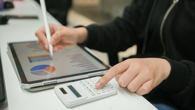 close up accountant businesswoman hand use calculator to summarize price and write on digital tablet to check report form marketing team for business strategy and performance concept - Powered by Adobe