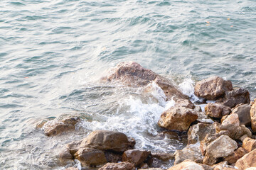 Splashes from the waves bumping against the rocky shore. which is an important tourist destination of Thailand. The background image is a sea blue of bright sunlight make the picture very bright.